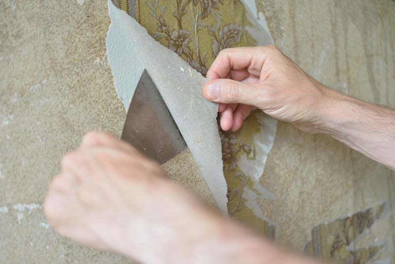A person using a knife to cut wallpaper